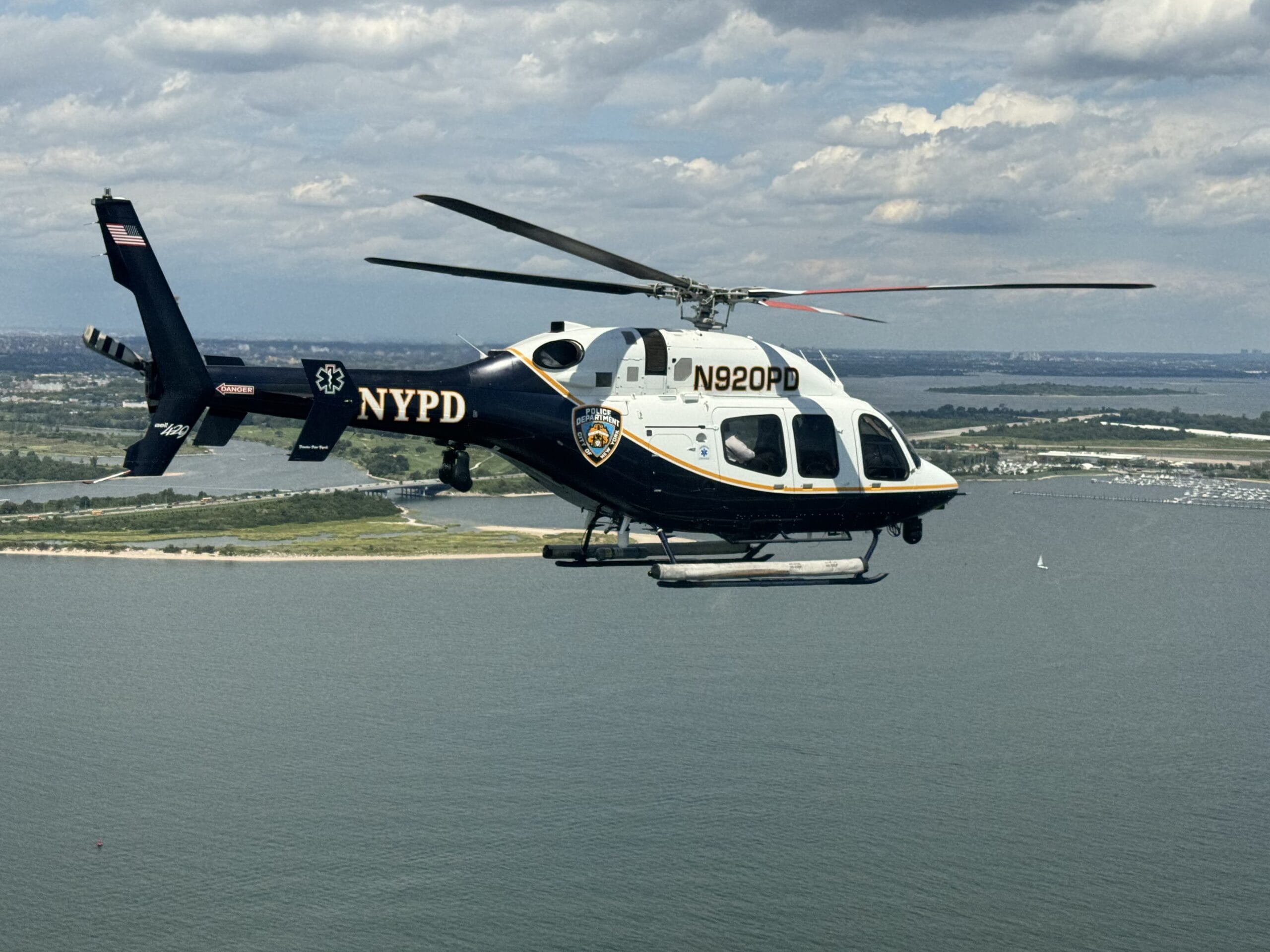 NYPD helicopter flying over scenic waterfront, showcasing law enforcement aerial capabilities and urban landscape.
