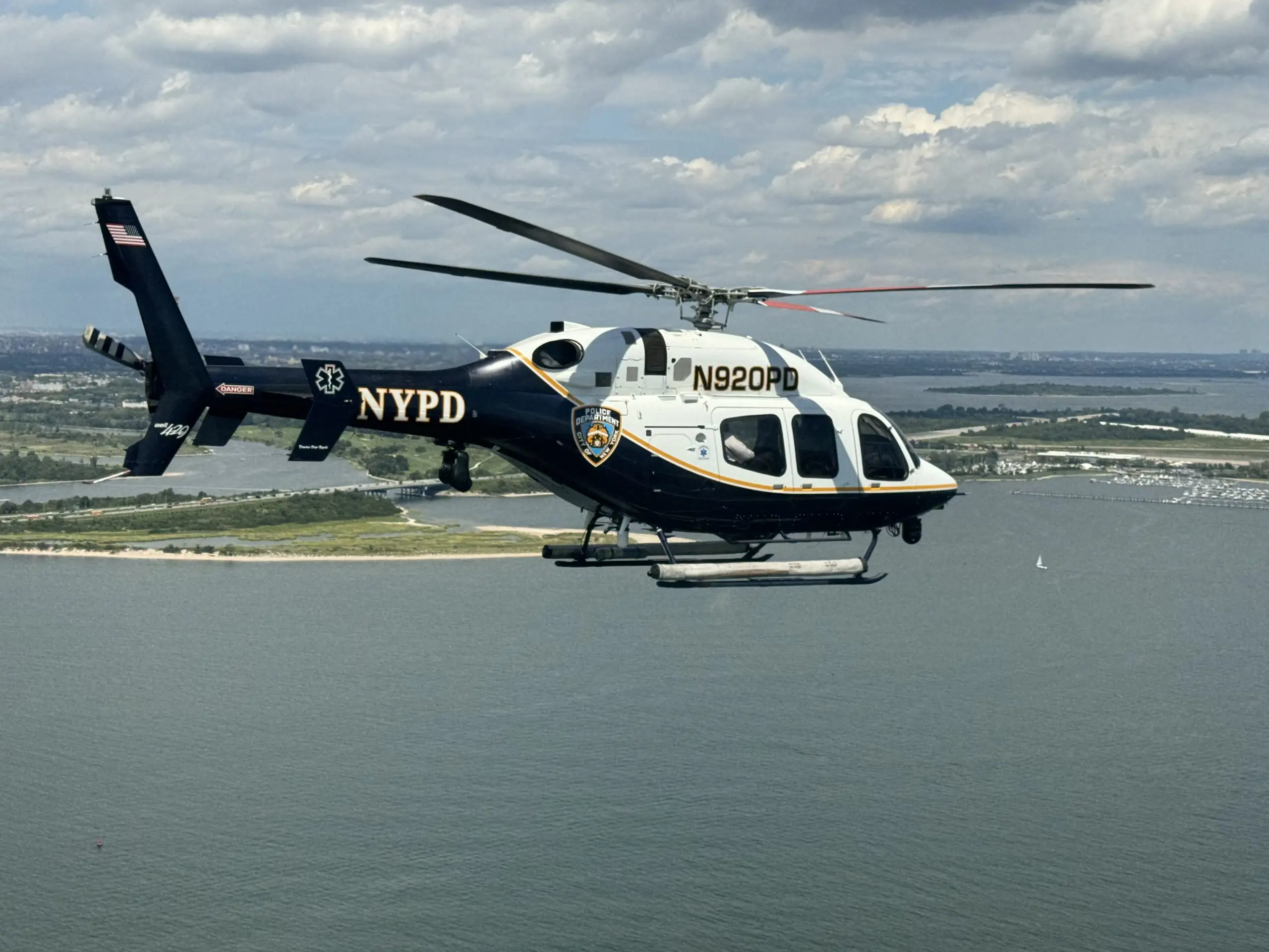 NYPD helicopter flying over scenic waterfront, showcasing law enforcement aerial capabilities and urban landscape.